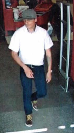 Man exiting target dressed in grey baseball cap, white short sleeve dress shirt, glasses, jeans with black belt, and brown lace up dress shoes. Man appears to have a left forearm tattoo.